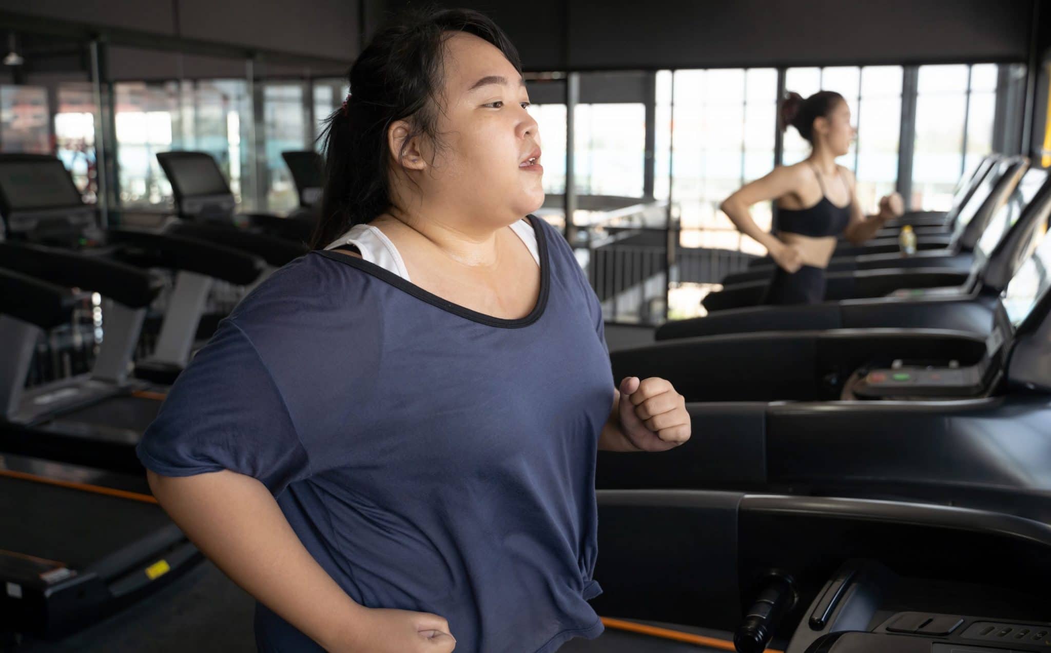 Fat woman running on a treadmill at gym