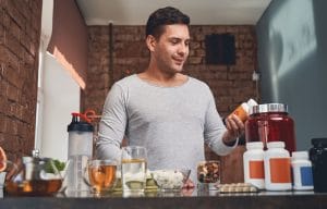 Fit man examining a dietary supplement in his hand 2021